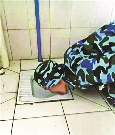 图中,一身着迷彩军训服的男生跪地用舌头舔厕所便池边沿,该男生在回复